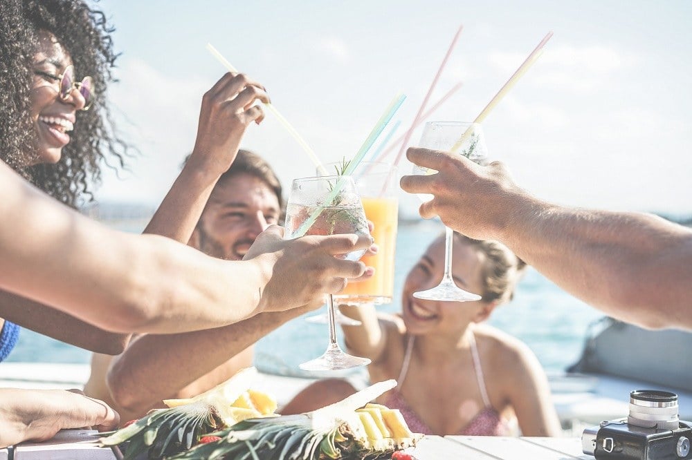Happy friends drinking tropical cocktails at boat party