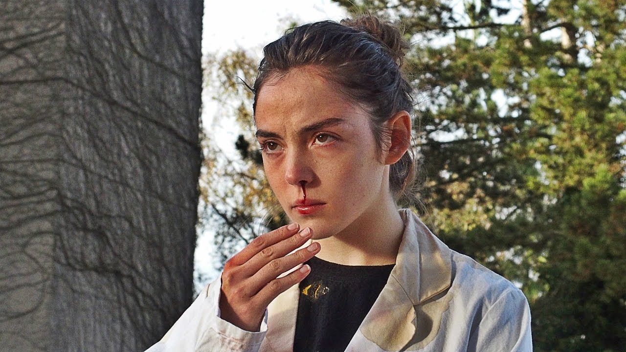 A girl holds a hand up in front of a bloody nose A girl holds a hand up in front of a bloody nose