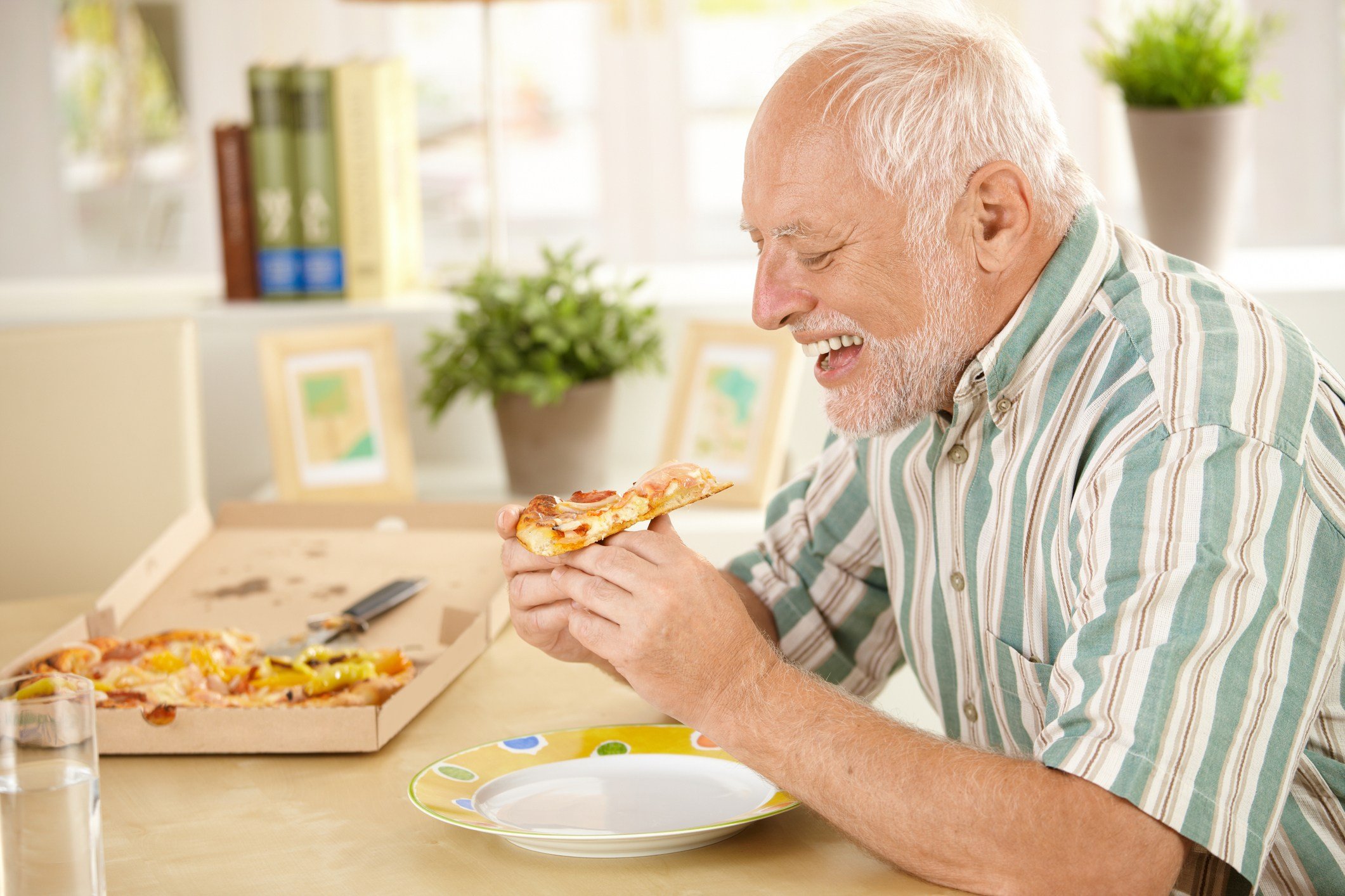 Smiling older man eating pizza