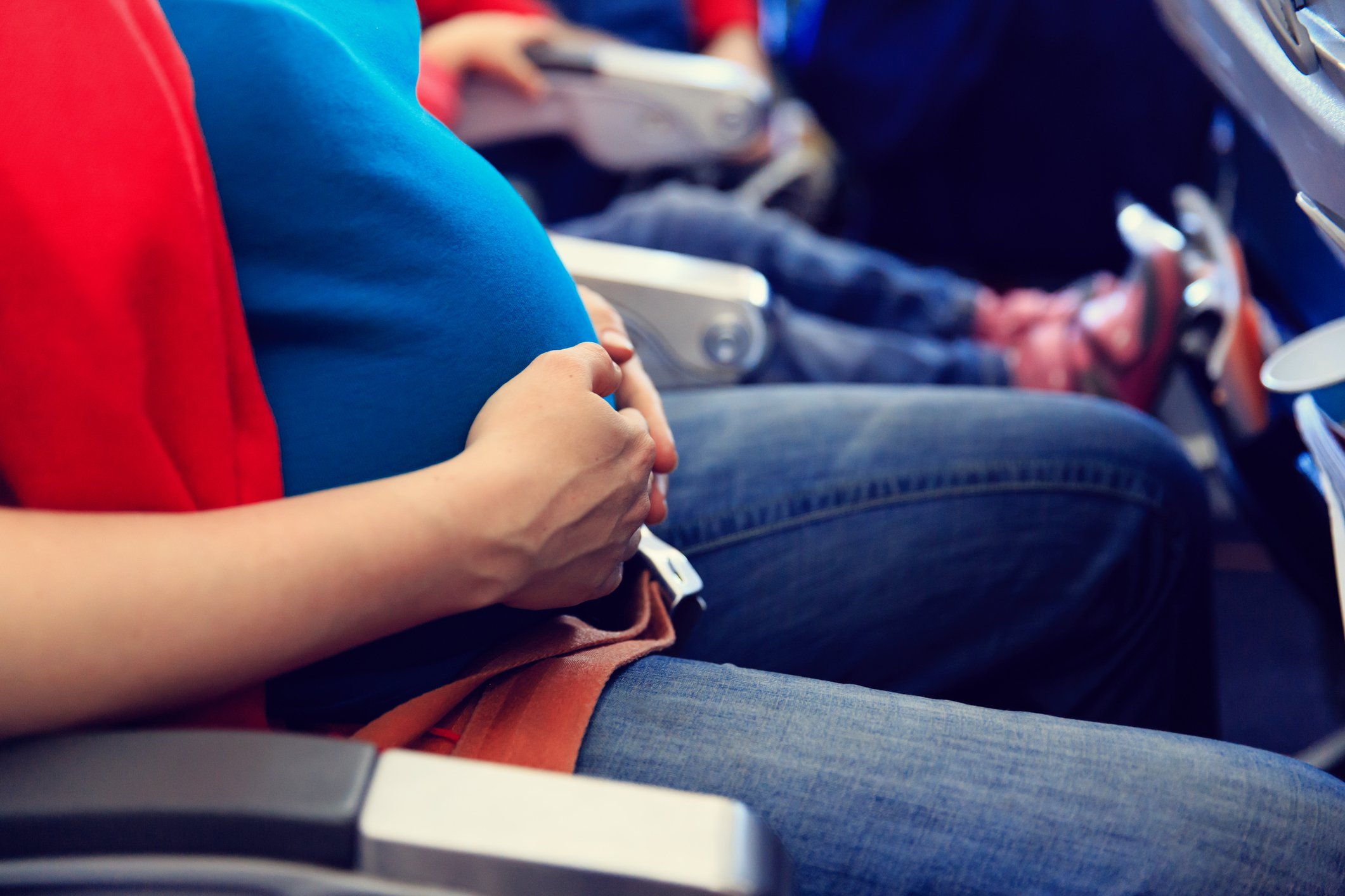 Pregnant woman holding her stomach on a plane