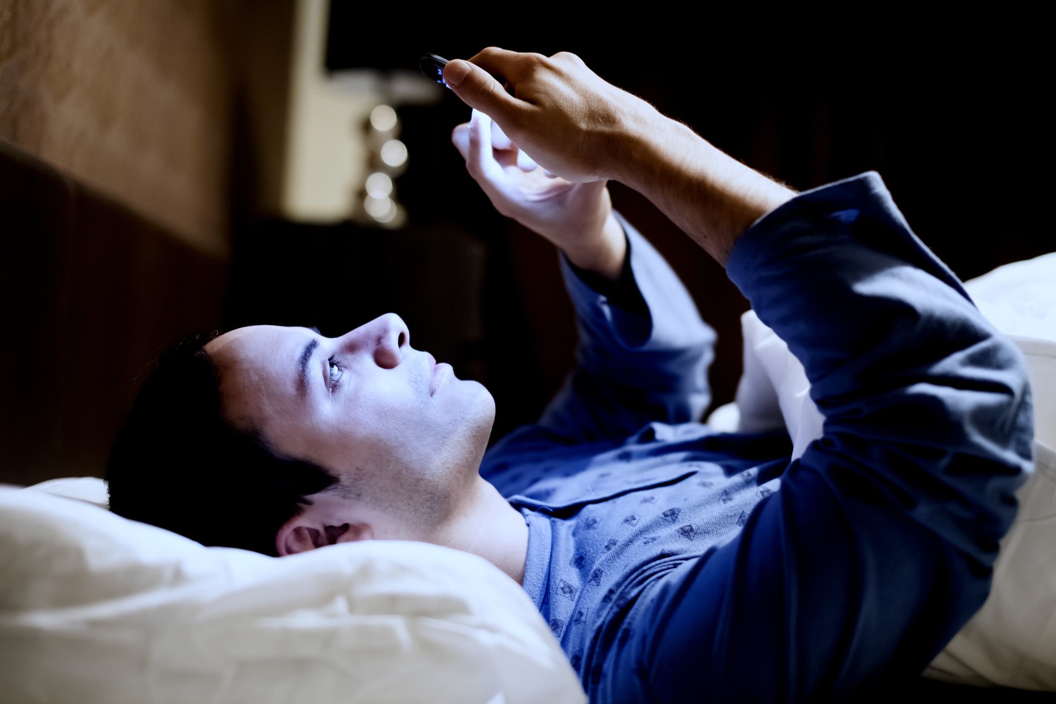 Man using his mobile phone in the bed Man using his mobile phone in the bed