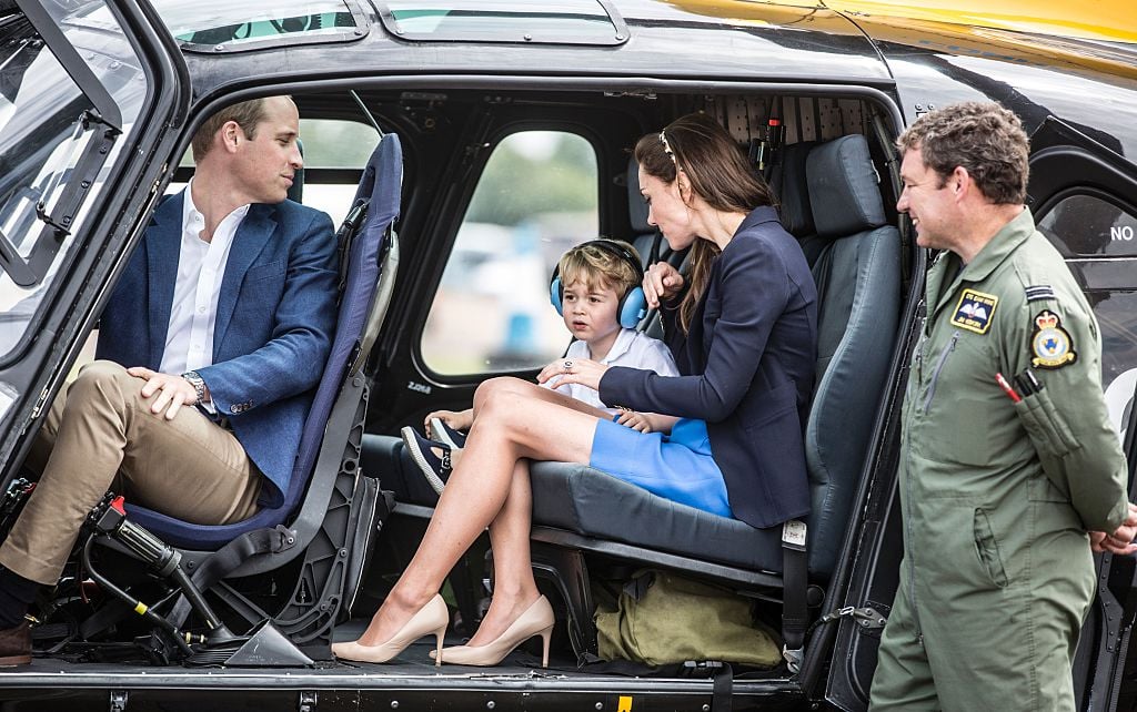 Britain's Prince George sits in a 'Squirrel' helicopter with his mother Catherine, Duchess of Cambridge and father Prince William during a visit to the Royal International Air Tattoo at RAF Fairford