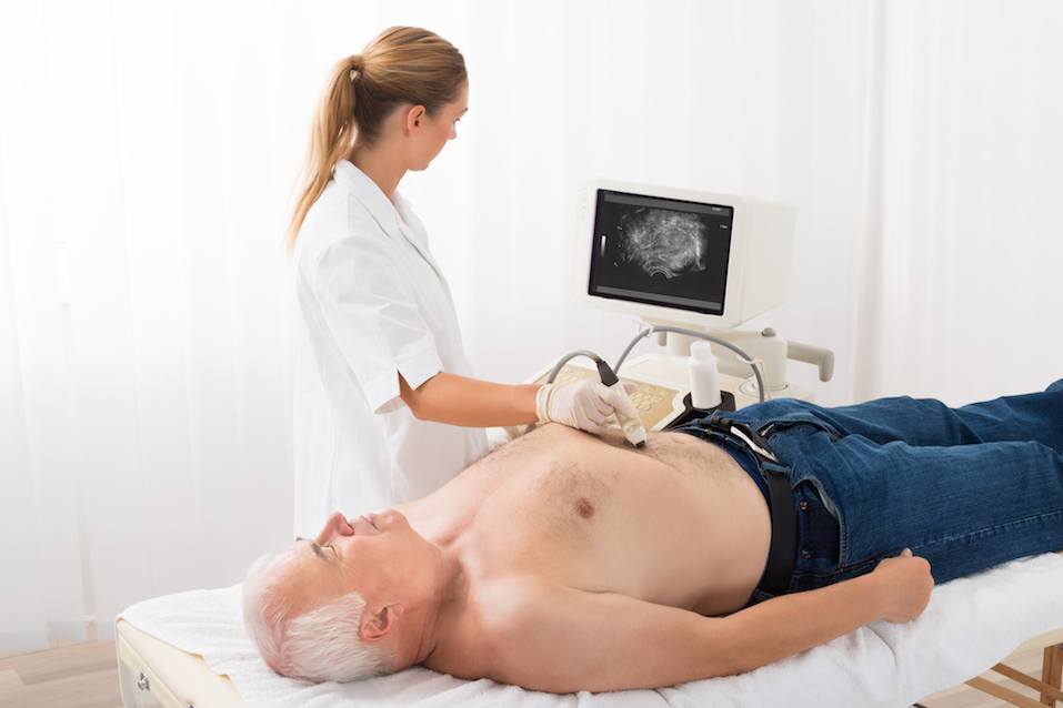 Doctor Using Ultrasound Scan On Abdomen Of Senior Male Patient