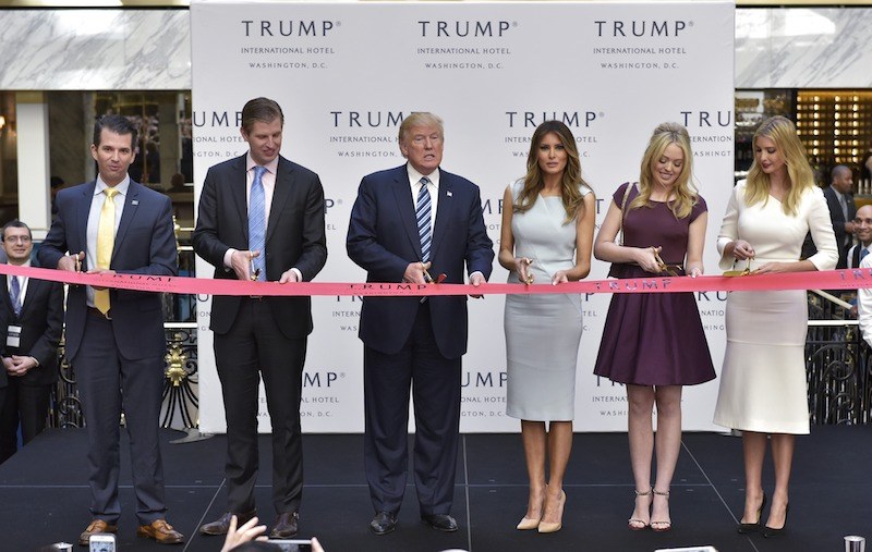 The Trump family lined behind a tape at a grand opening event. The Trump family lined behind a tape at a grand opening event.