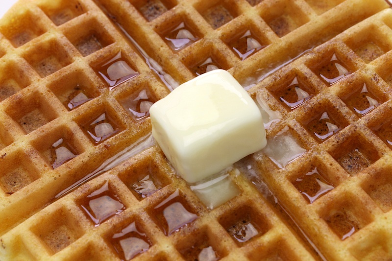 A waffle with syrup and butter. 
