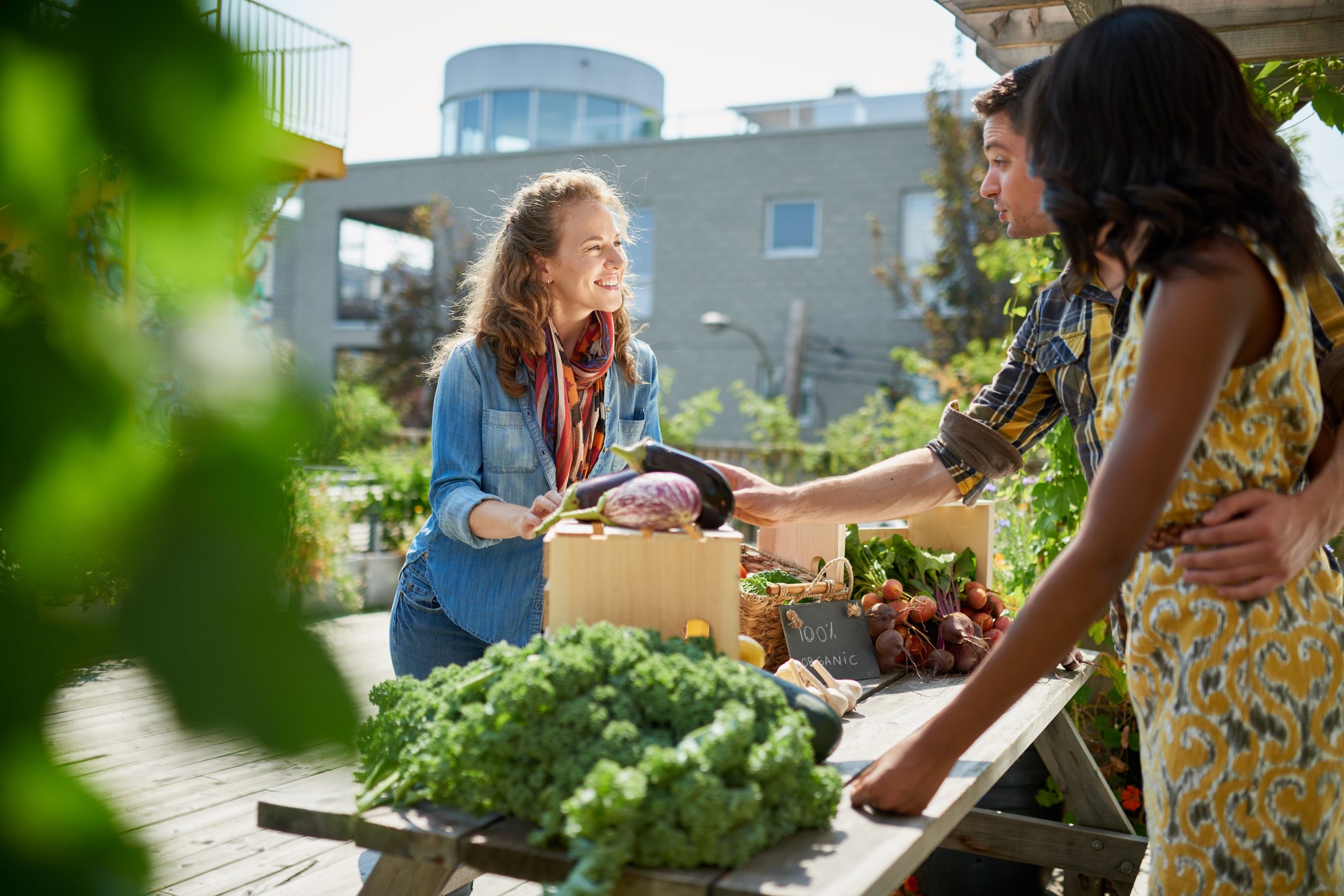 Friendly woman tending an organic vegetable stall at a farmer