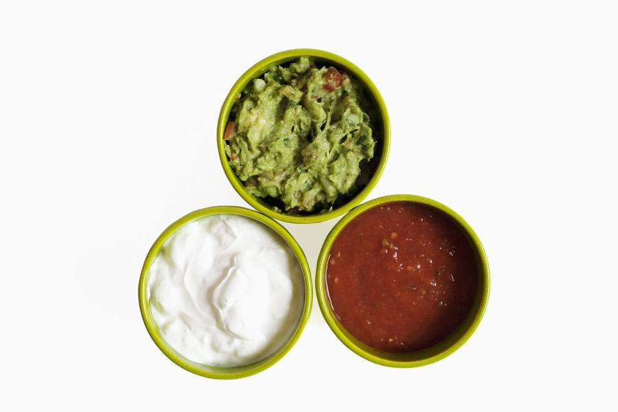 Three bowls filled with salsa guacamole and sour cream, close-up Three bowls filled with salsa guacamole and sour cream, close-up