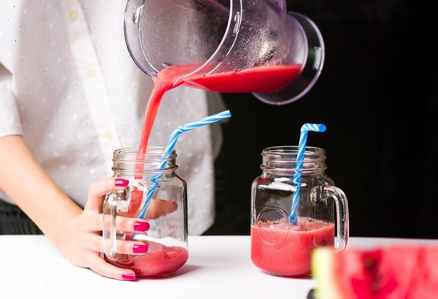 A smoothie being poured into mason jars A smoothie being poured into mason jars