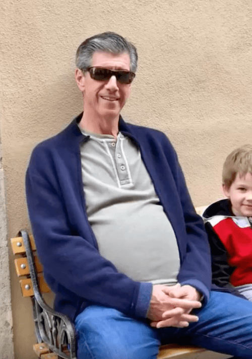Kevin Daly sitting on a bench with a small child next to him. Kevin Daly sitting on a bench with a small child next to him.