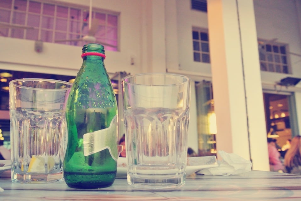 seltzer waterbottle and two glasses on the table in an open air cafe or restaurant