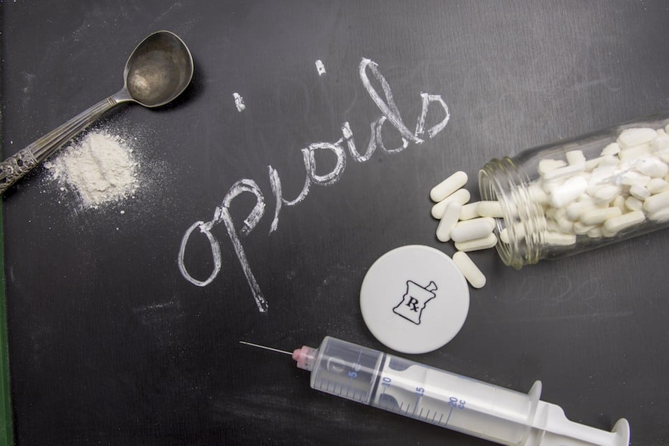 Opioids written in chalk on blackboard with crushed powder, spoon, syringe, and prescription vial. Opioids written in chalk on blackboard with crushed powder, spoon, syringe, and prescription vial.