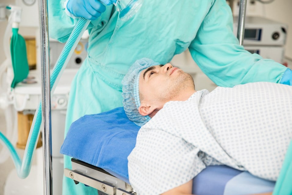 Male patient lying on a hospital bed and ready to be put under anesthesia Male patient lying on a hospital bed and ready to be put under anesthesia