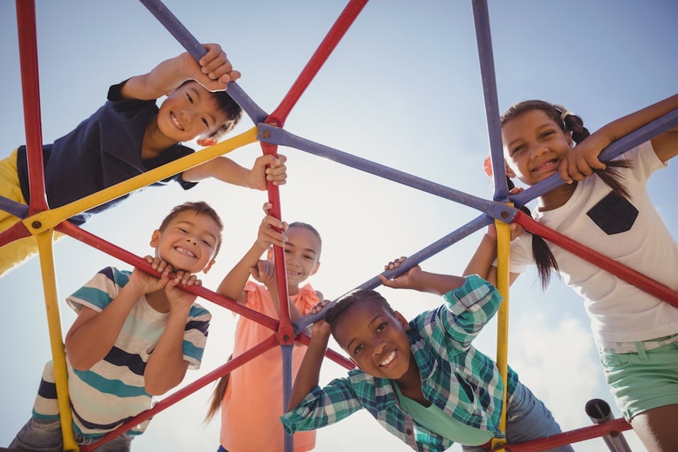 happy schoolkids looking through dome climber at school playground