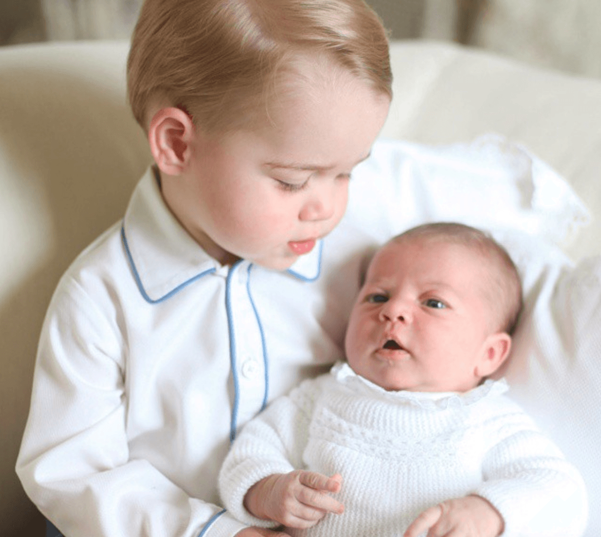Prince George holding Princess Charlotte