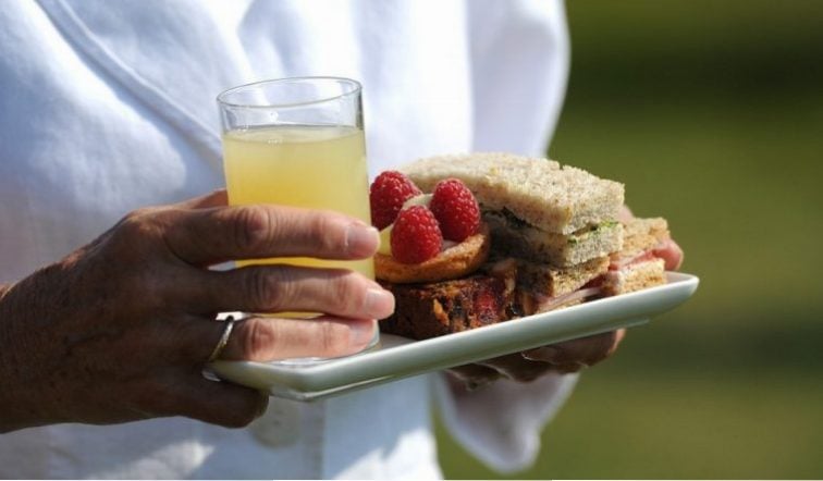 A woman carries sandwiches and cakes during a Garden Party Queen Elizabeth is hosting at Buckingham Palace