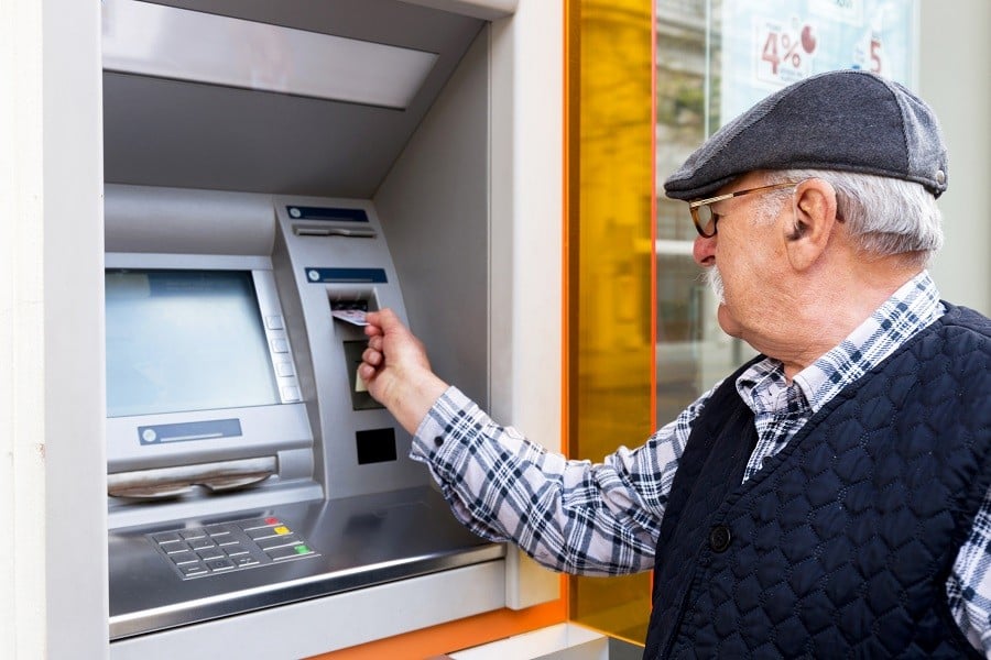 elderly man inserting credit card to ATM outdoor elderly man inserting credit card to ATM outdoor