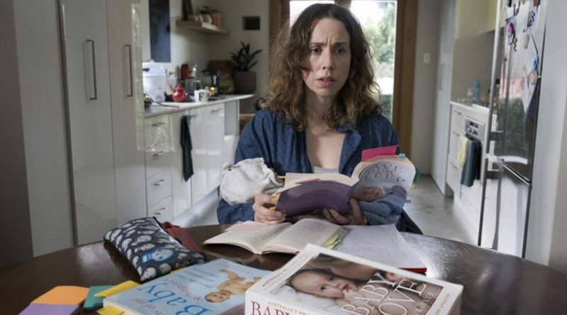 A woman holds a baby and holds up parenting books. A woman holds a baby and holds up parenting books.