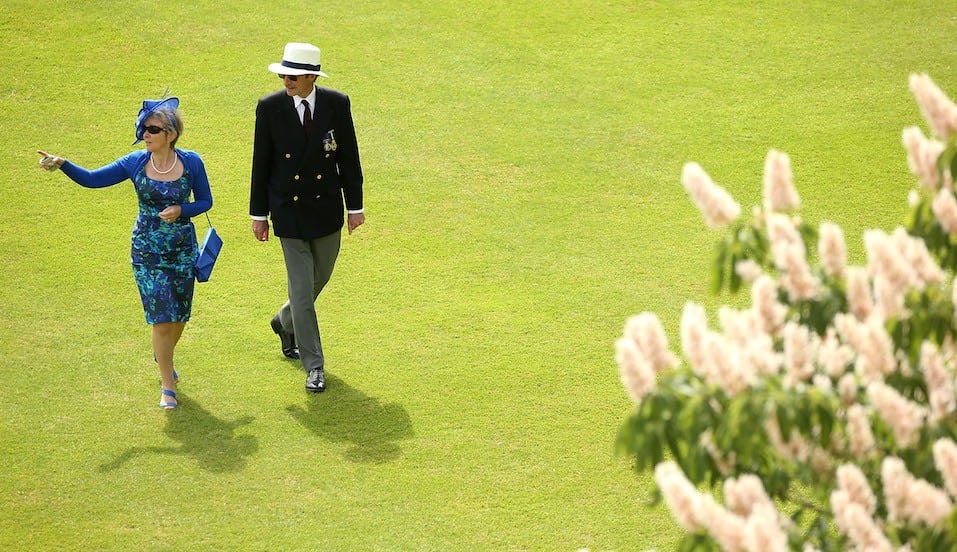 Guests walk across the Buckingham Palace lawn during a Garden Party at Buckingham Palace