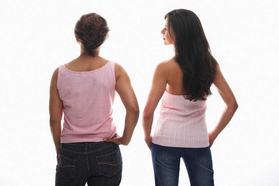Young woman and mature woman standing with hands on hips