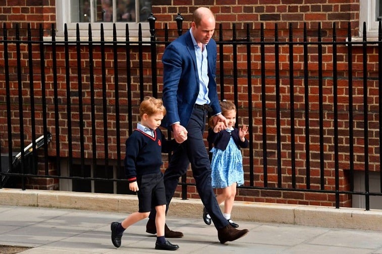 Prince George, Prince William, and Princess Charlotte in front of a hospital. 