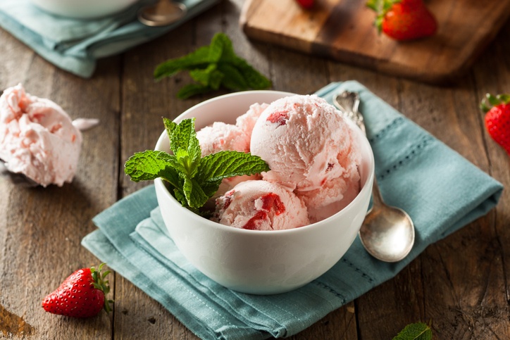 Scoops of strawberry ice cream in a dish with mint garnish