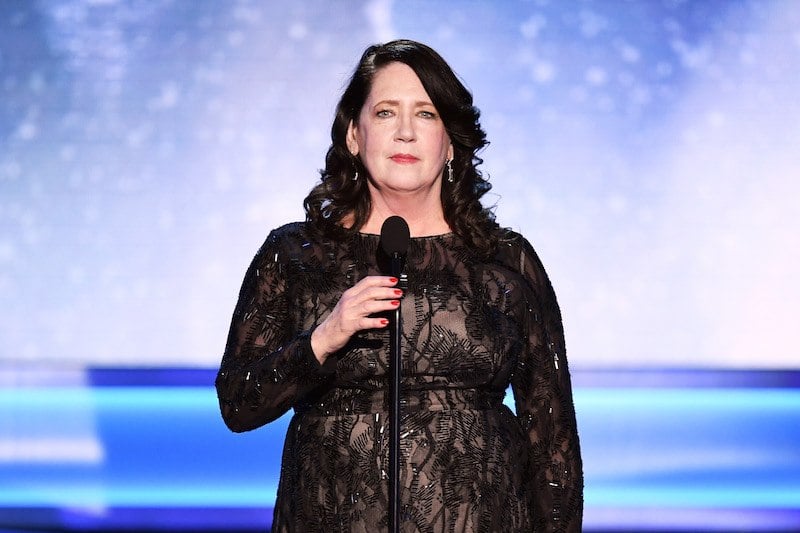 Ann Dowd speaking while wearing a black dress on stage. Ann Dowd speaking while wearing a black dress on stage.