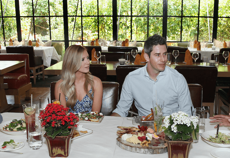 Arie Luyendyk Jr. and Lauren Burnham at a dinner table together. 