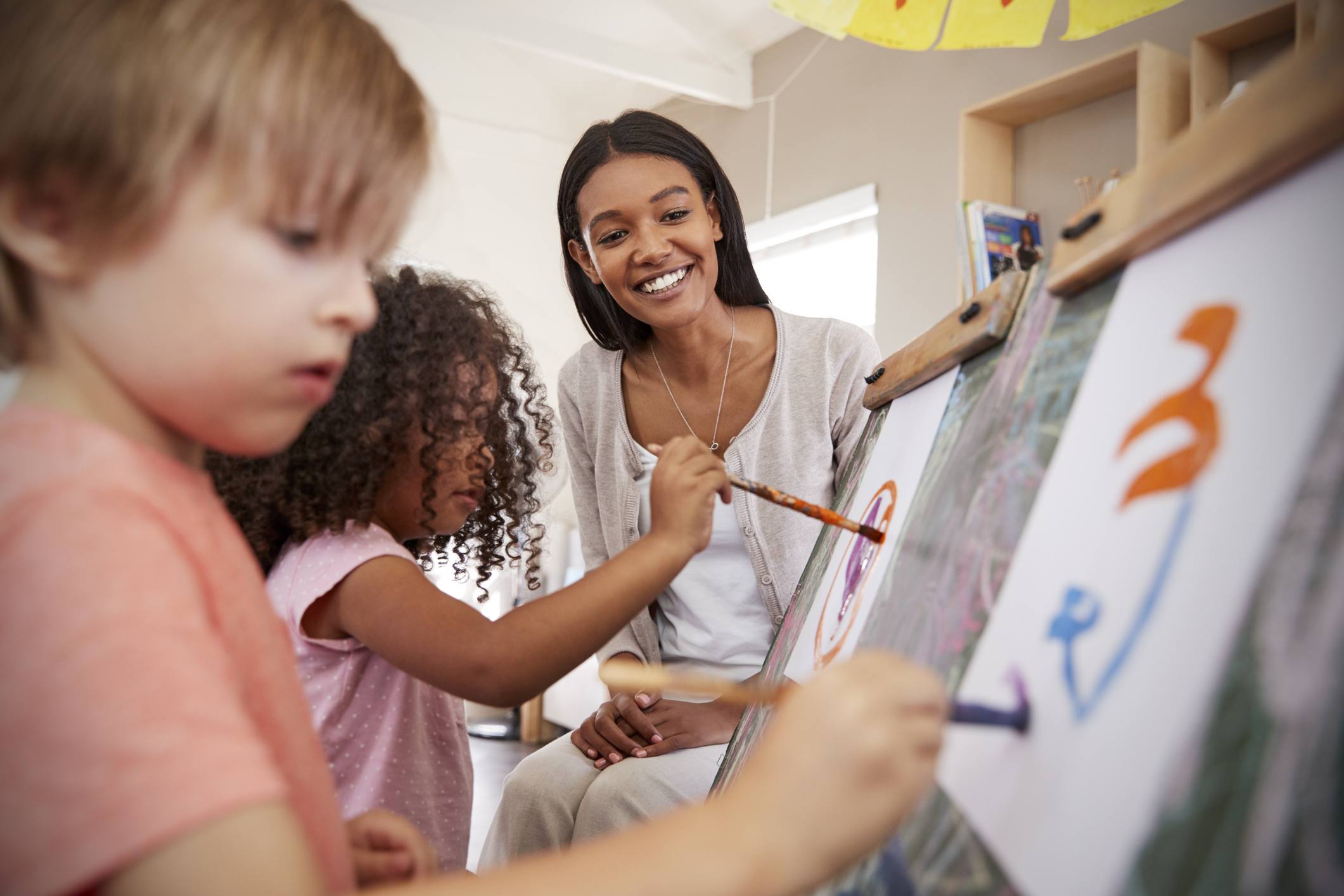 Teacher At Montessori School Helping Children in Art Class