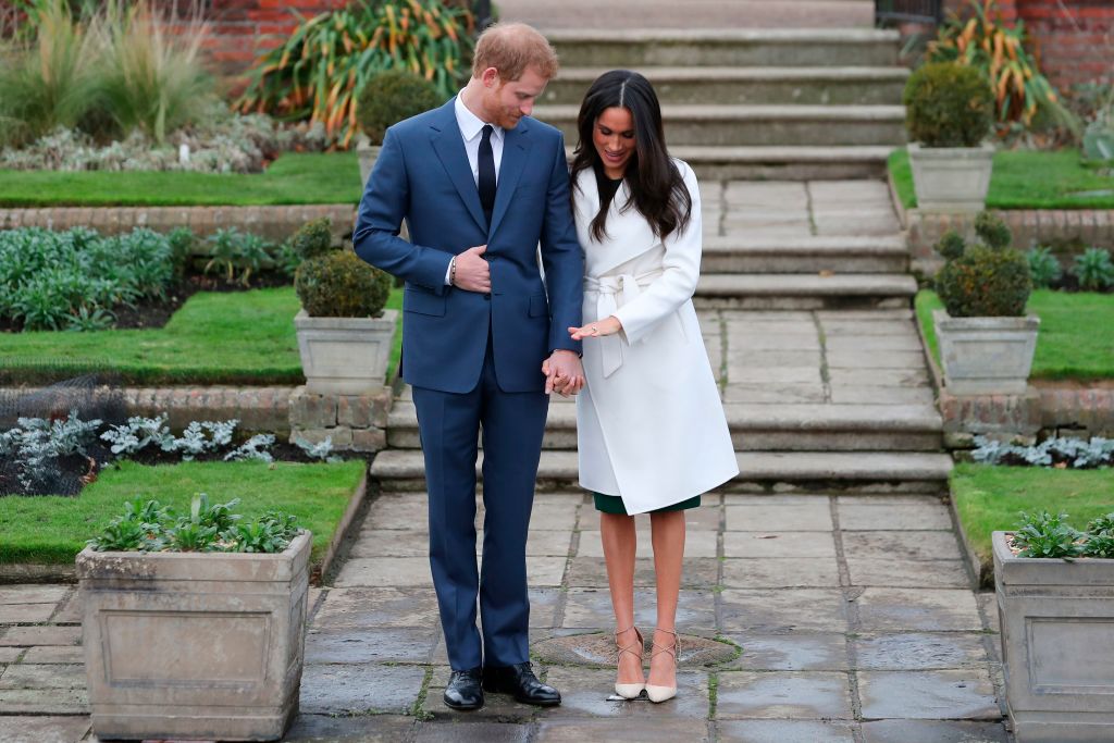Britain's Prince Harry stands with his fiancée US actress Meghan Markle as she shows off her engagement ring