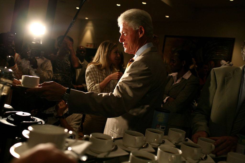 Bill Clinton samples coffee as his daughter Chelsea Clinton looks on.