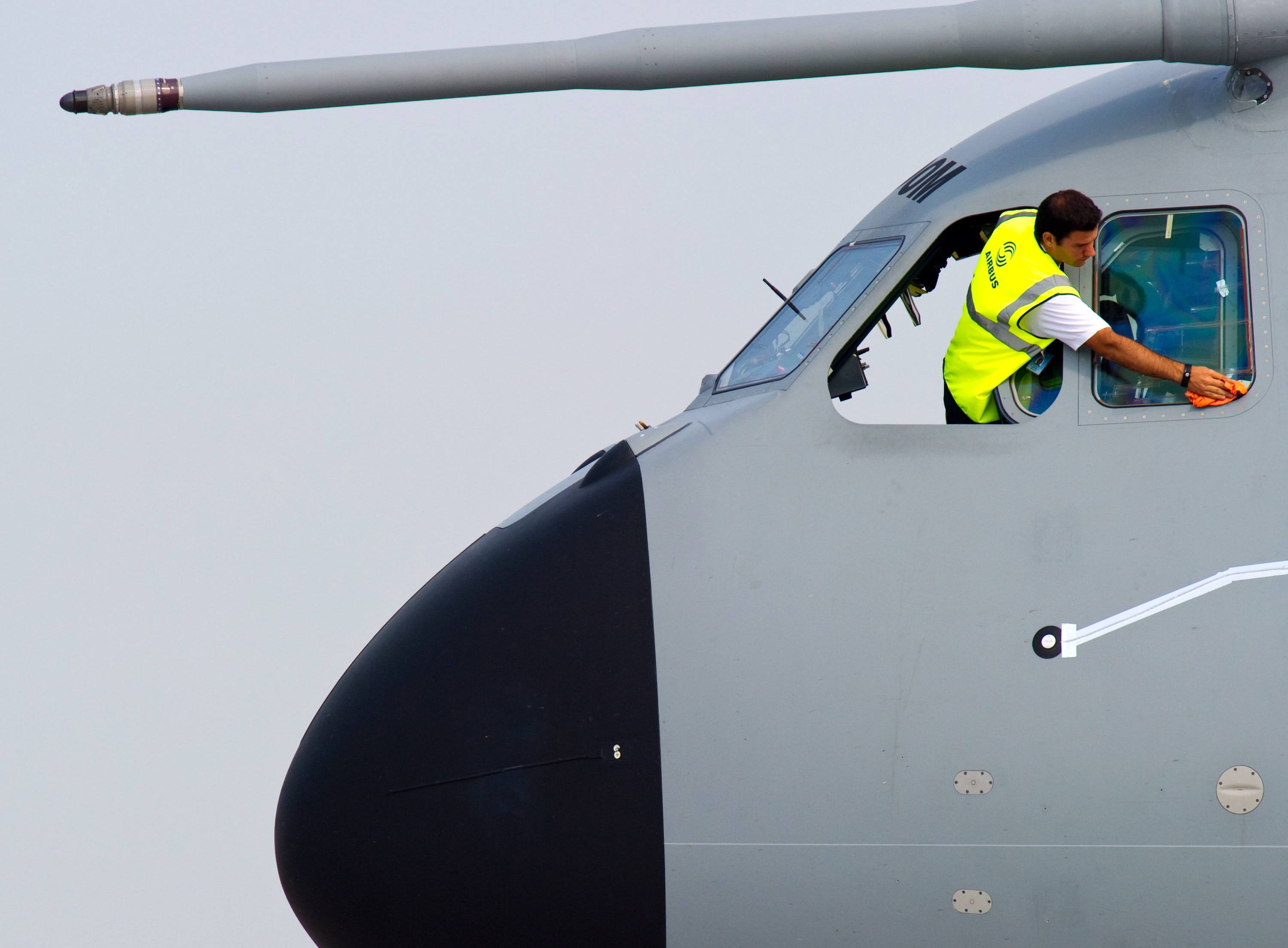 A man cleans the cockpit windows of an Airplane