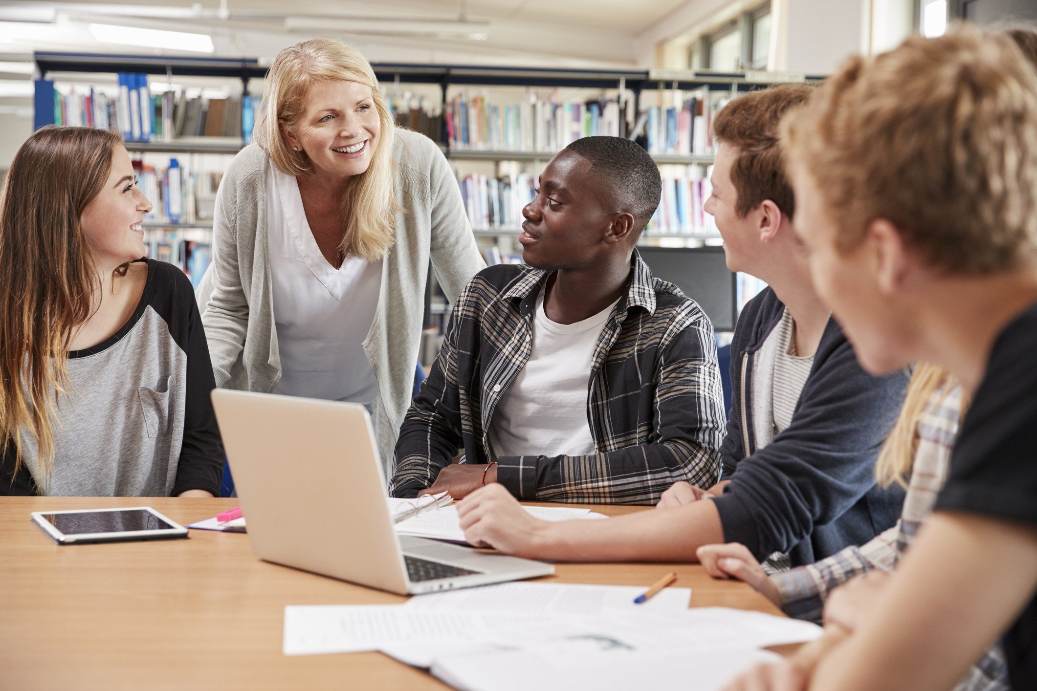 Female Teacher Working With College Students In Library