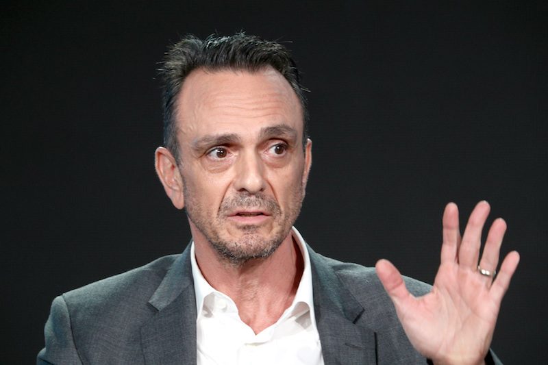 Hank Azaria raising up his hand during a stage talk. Hank Azaria raising up his hand during a stage talk.