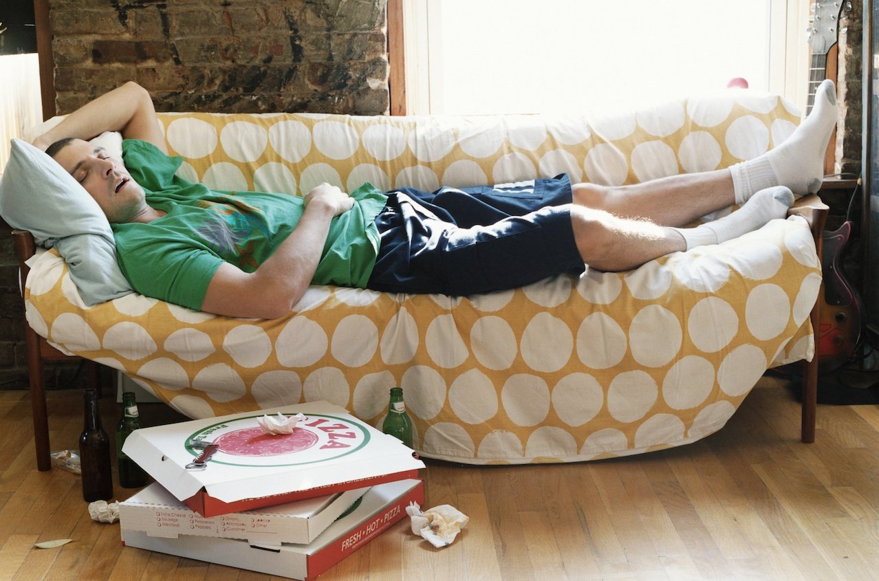 Lazy Thirty something Man Lying Asleep on a Sofa in an Apartment