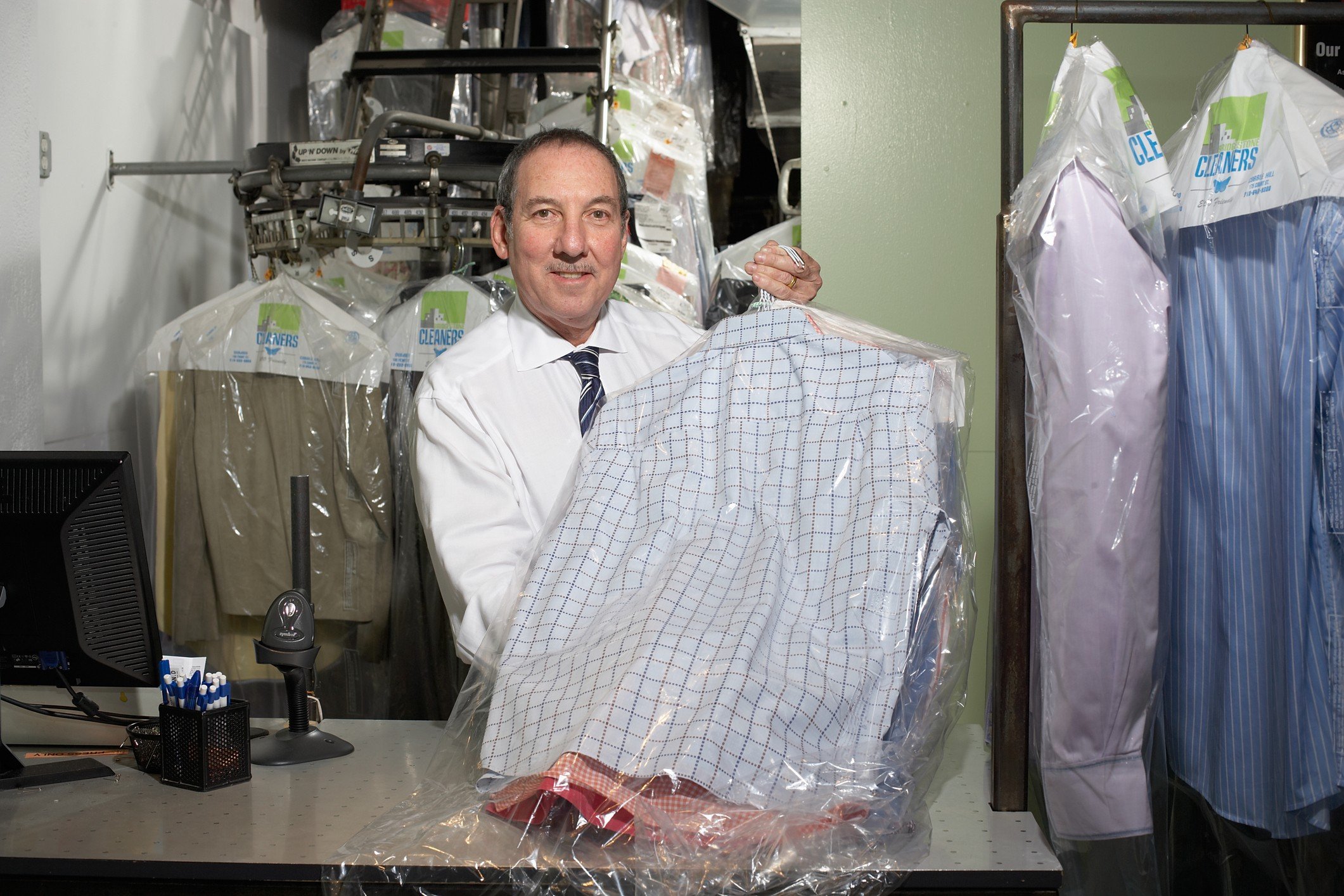 Dry cleaners operator holding shirts on hangers, portrait