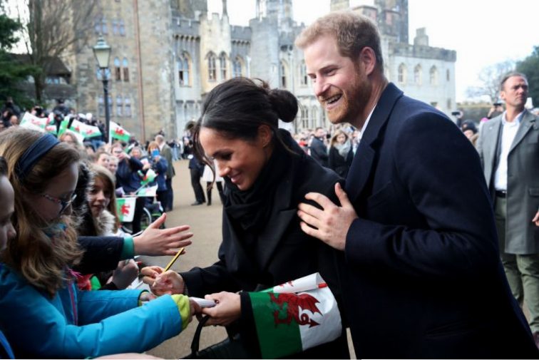 Prince Harry and his fiancee Meghan Markle sign autographs and shake hands with children as they arrive to a walkabout at Cardiff Castle