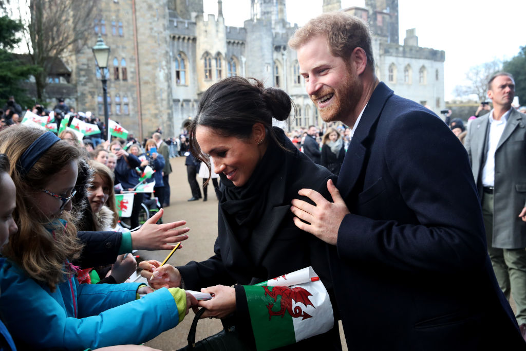 Prince Harry and his fiancee Meghan Markle sign autographs and shake hands with children as they arrive to a walkabout at Cardiff Castle