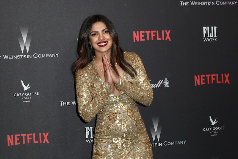 Priyanka Chopra in a gold dress on a red carpet. Priyanka Chopra in a gold dress on a red carpet.