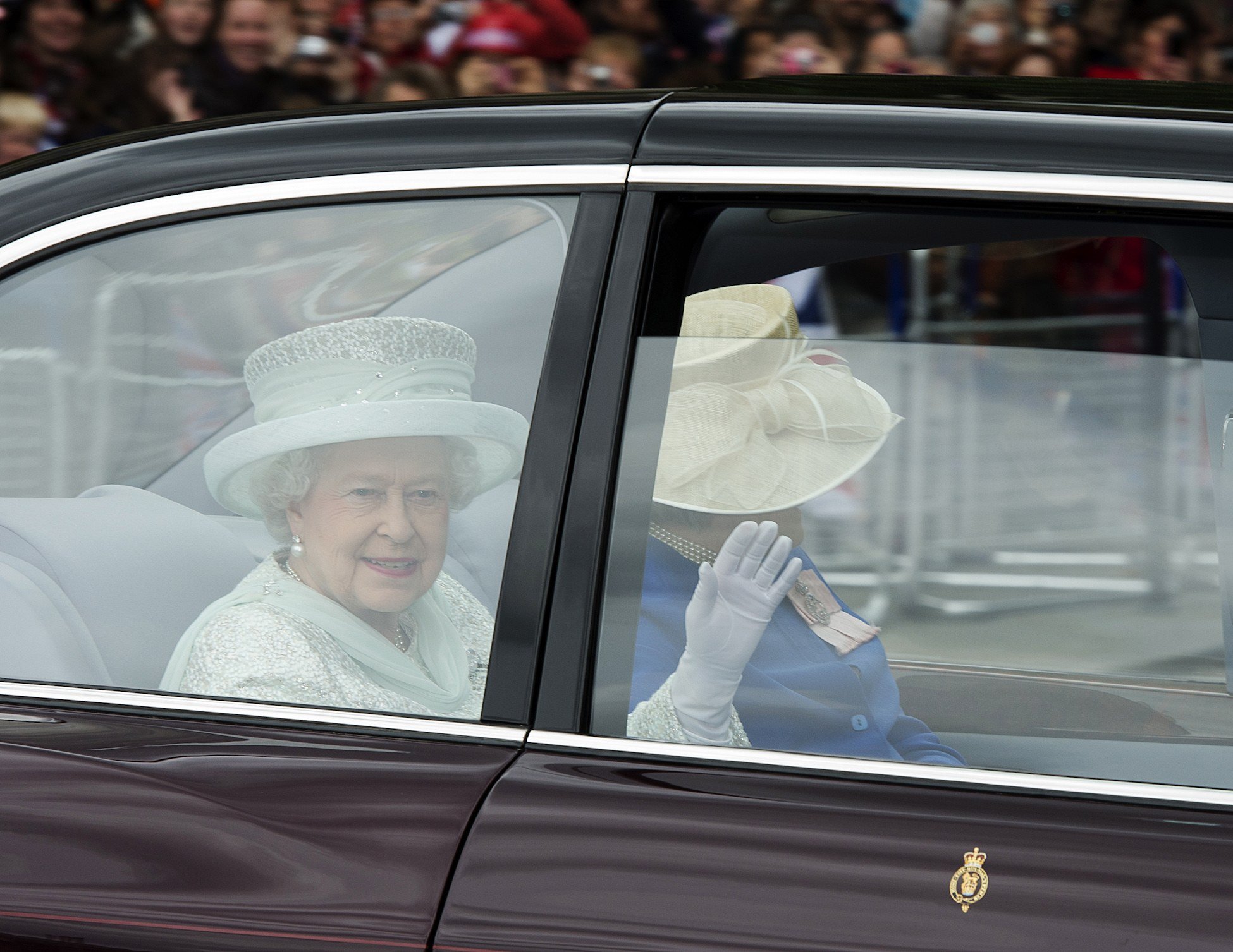 Britain's Queen Elizabeth II waves from the back of her State Limousine accompanied by a Lady in Waiting