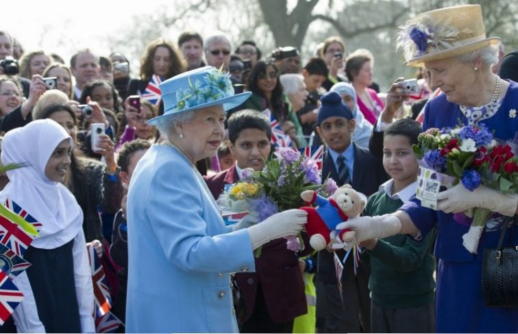Queen Elizabeth II (L) hands gifts she was presented with to a lady-in-waiting