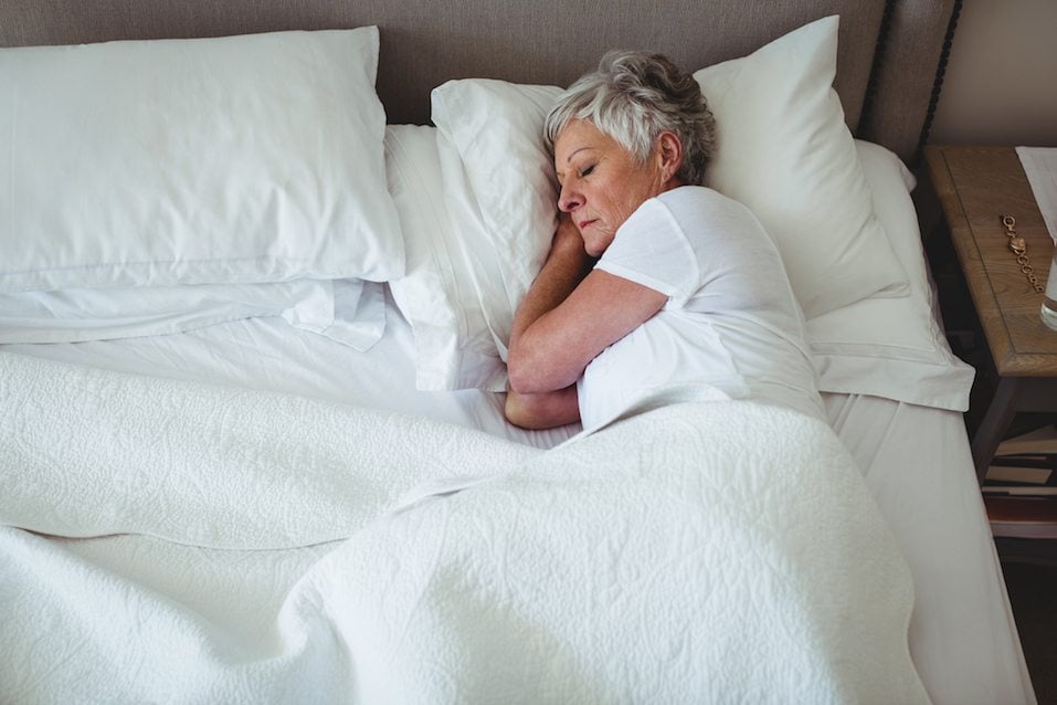 Senior woman sleeping on bed in bedroom at home