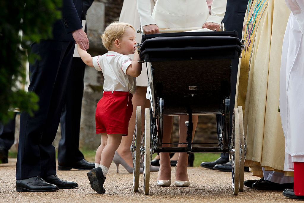 Catherine, Duchess of Cambridge and Prince William, Duke of Cambridge stand as Prince George of Cambridge looks into Princess Charlotte of Cambridge's pram