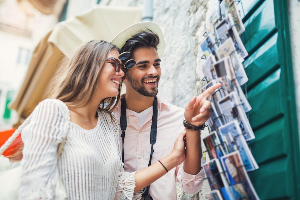 Tourist couple enjoying sightseeing exploring city and buy postcards
