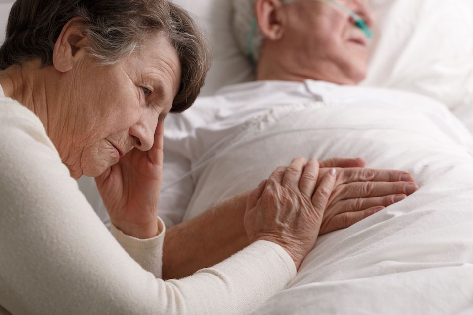 Woman holding dying husband's hand