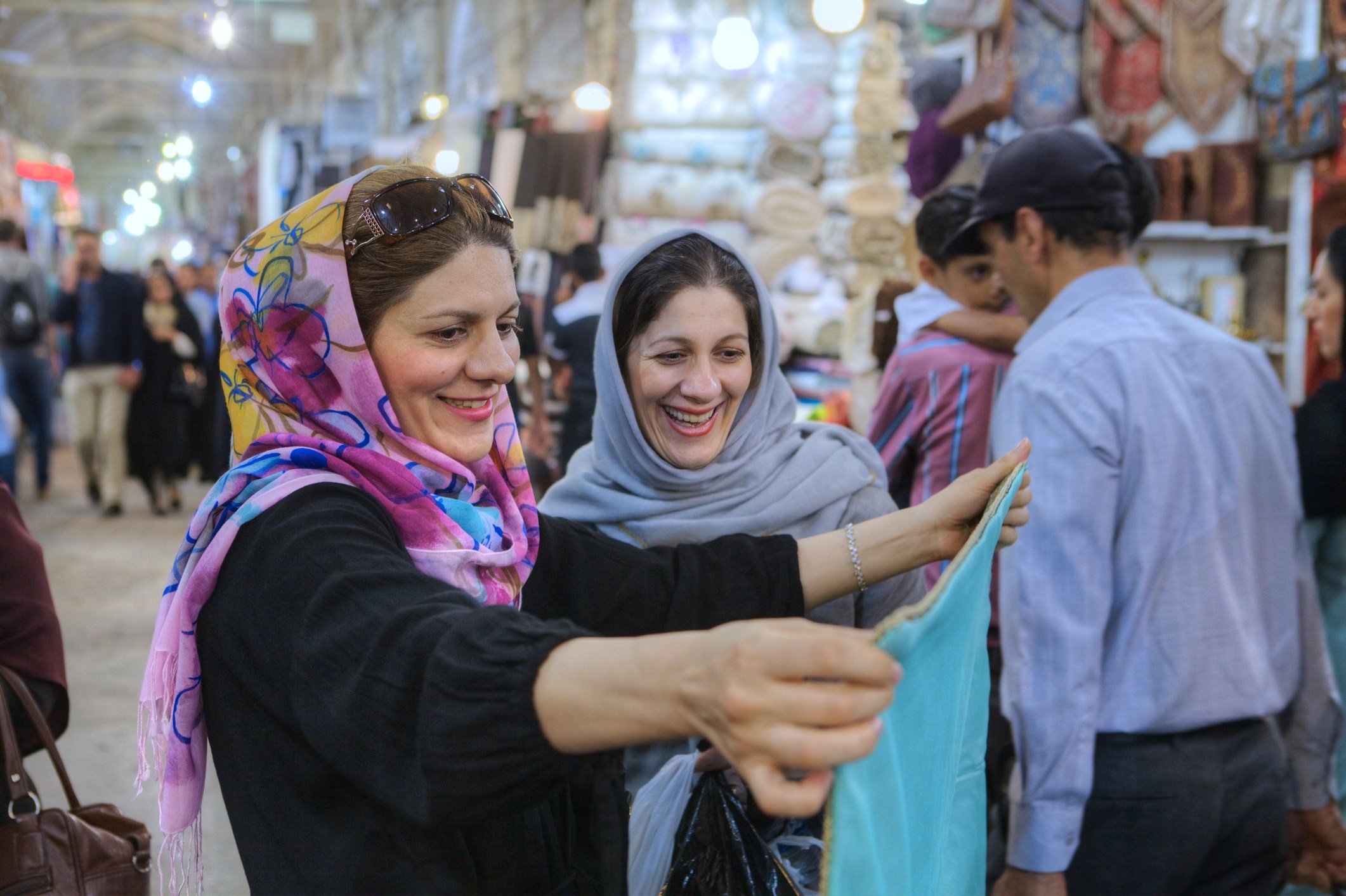 Women in hijab choose fabric in city market, Shiraz, Iran.