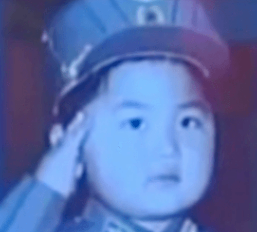 A young Kim Jong Un saluting in a photo. A young Kim Jong Un saluting in a photo.