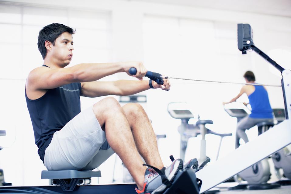 Young man exercising on a rowing machine in a gym