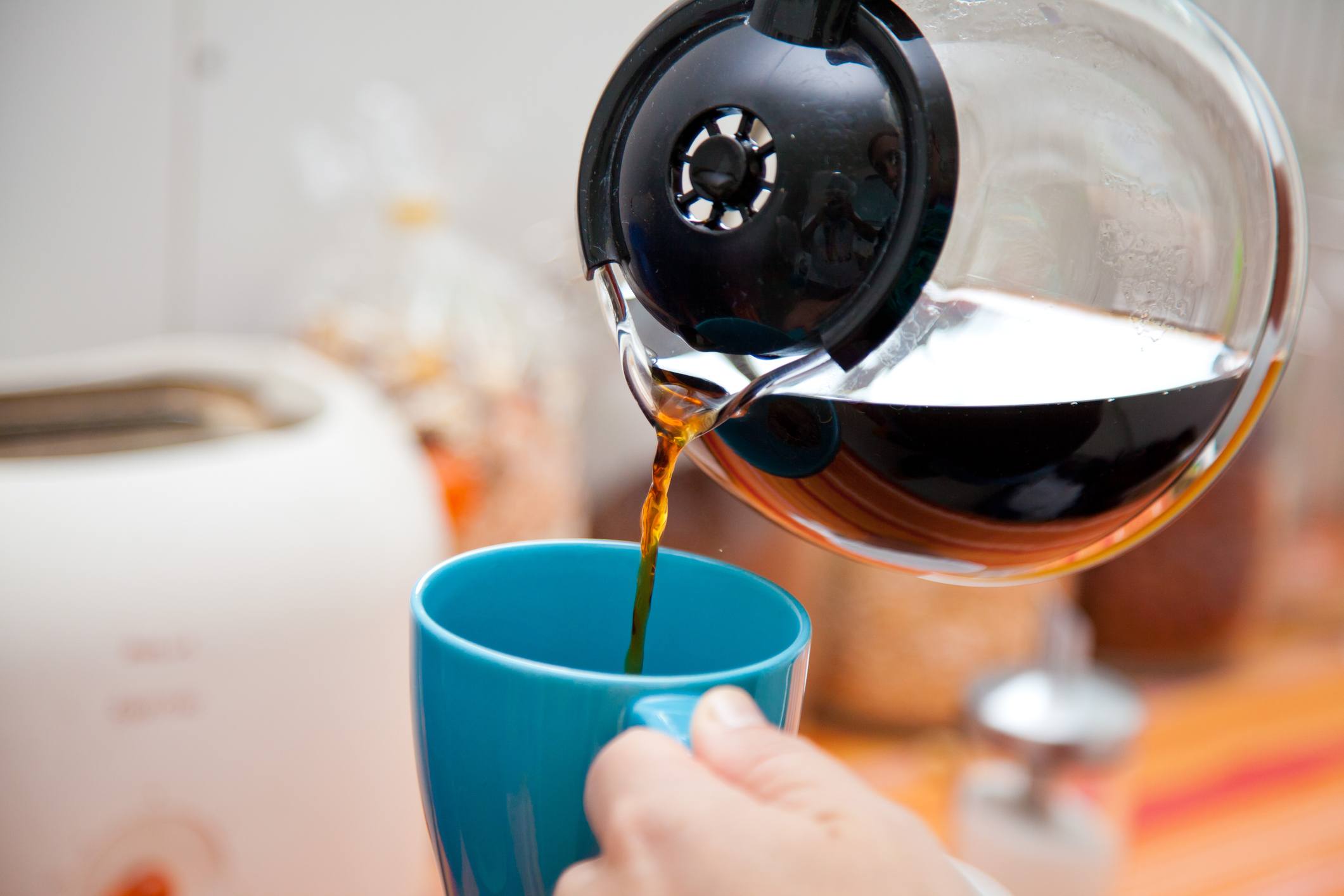 A person pours coffee from the pot. A person pours coffee from the pot.