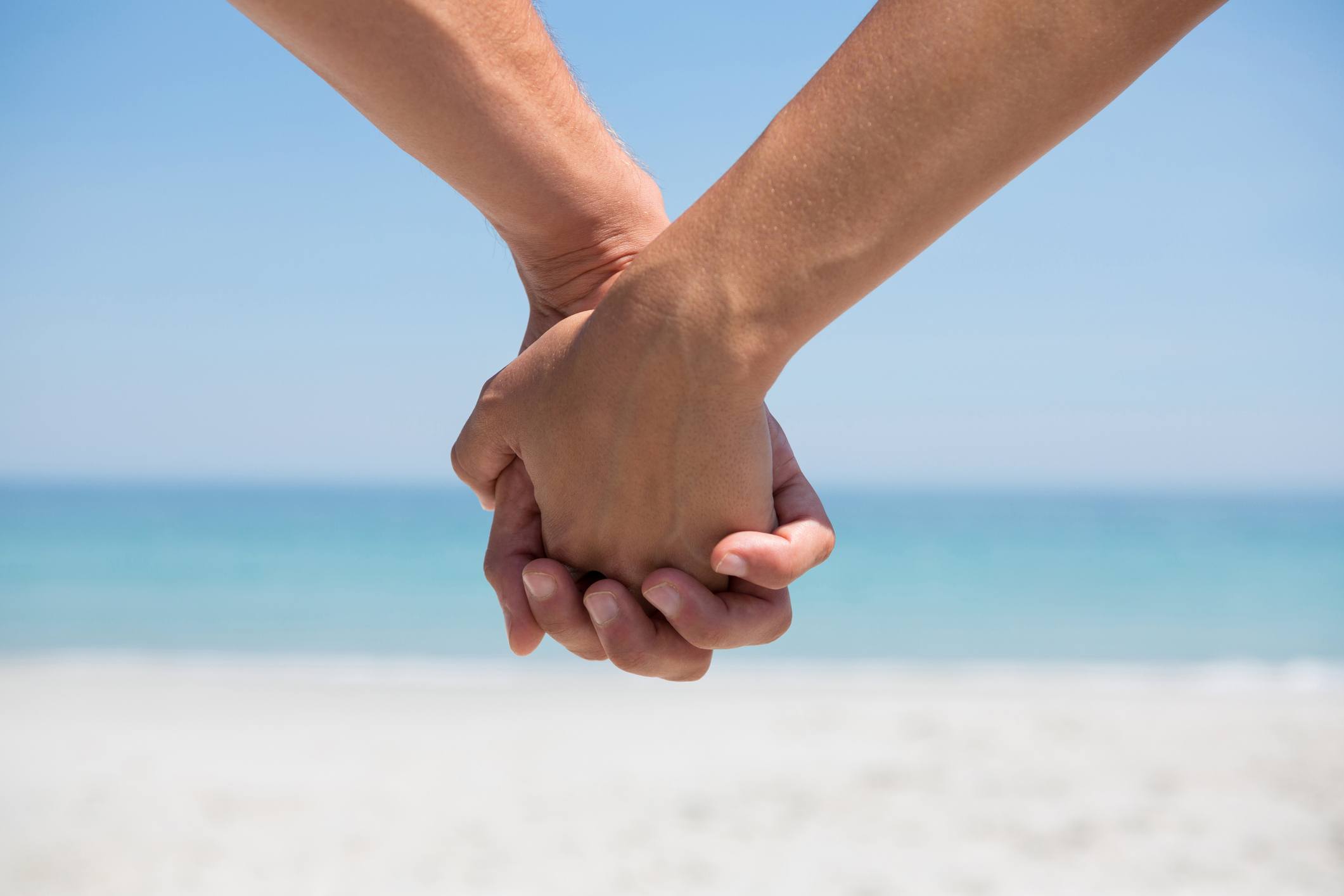 A couple holds hands at the beach.