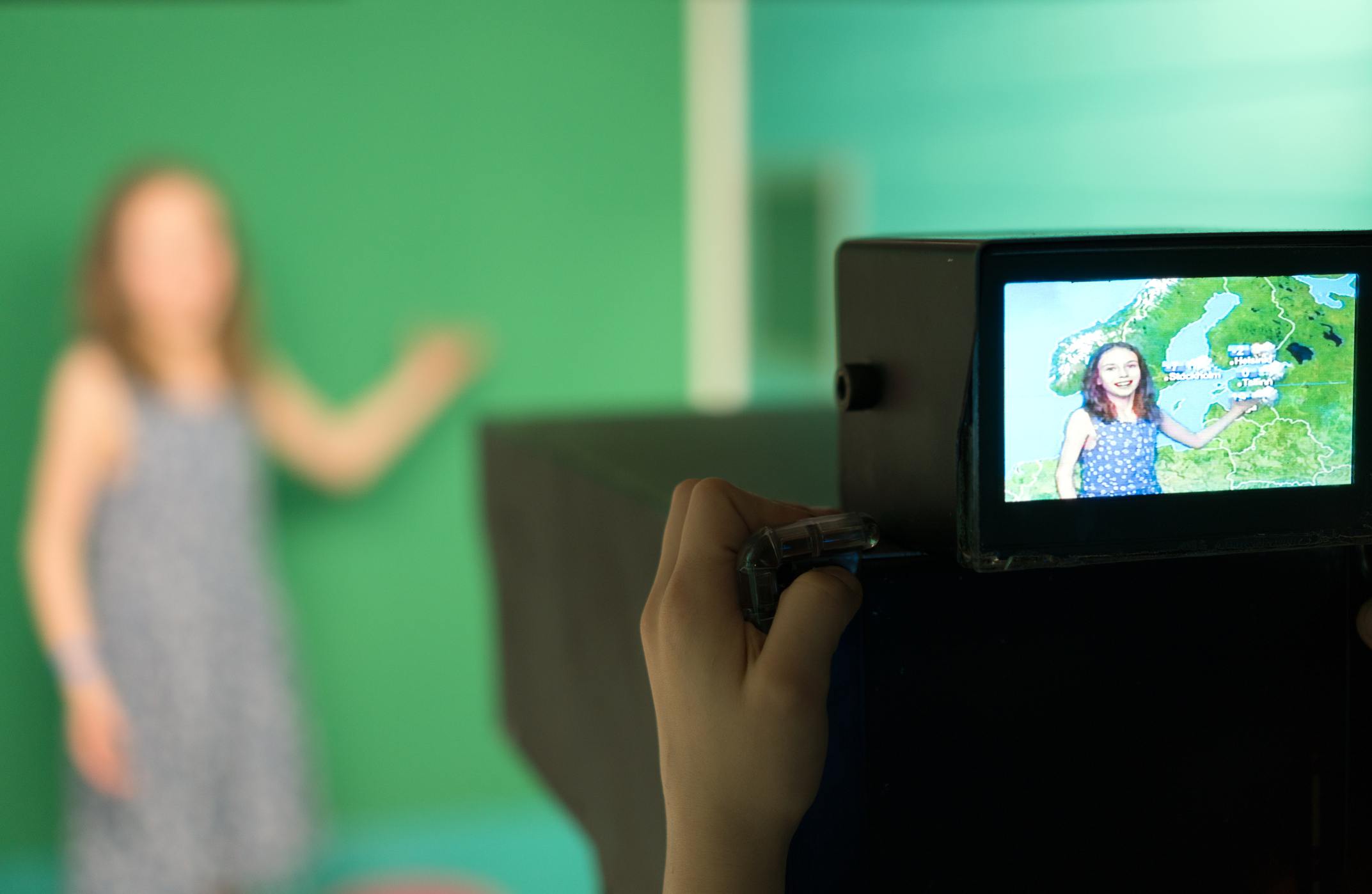Weather forecast. Little girl standing in front of camera on green screen.